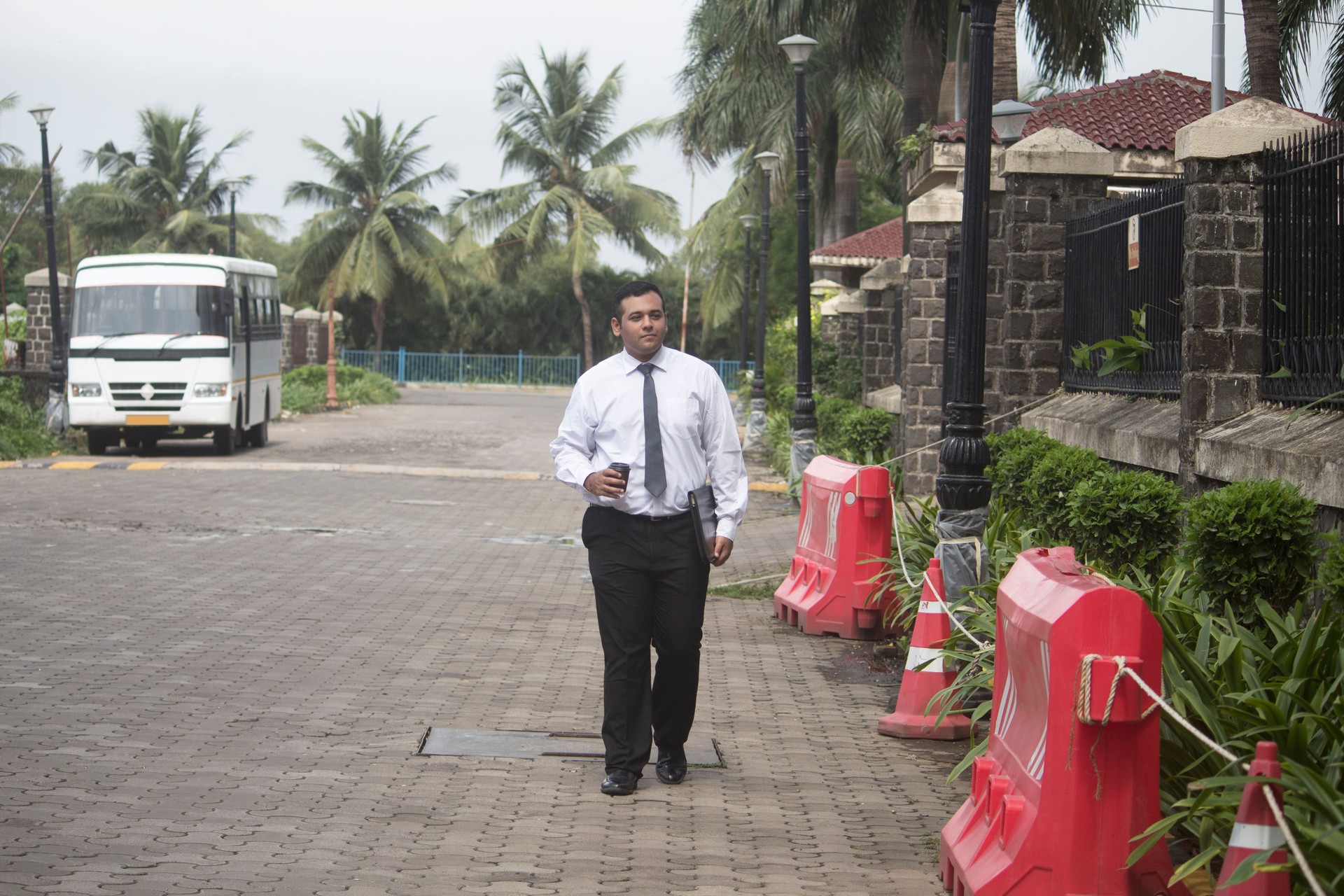 Businessman carrying disposable coffee cup and folder