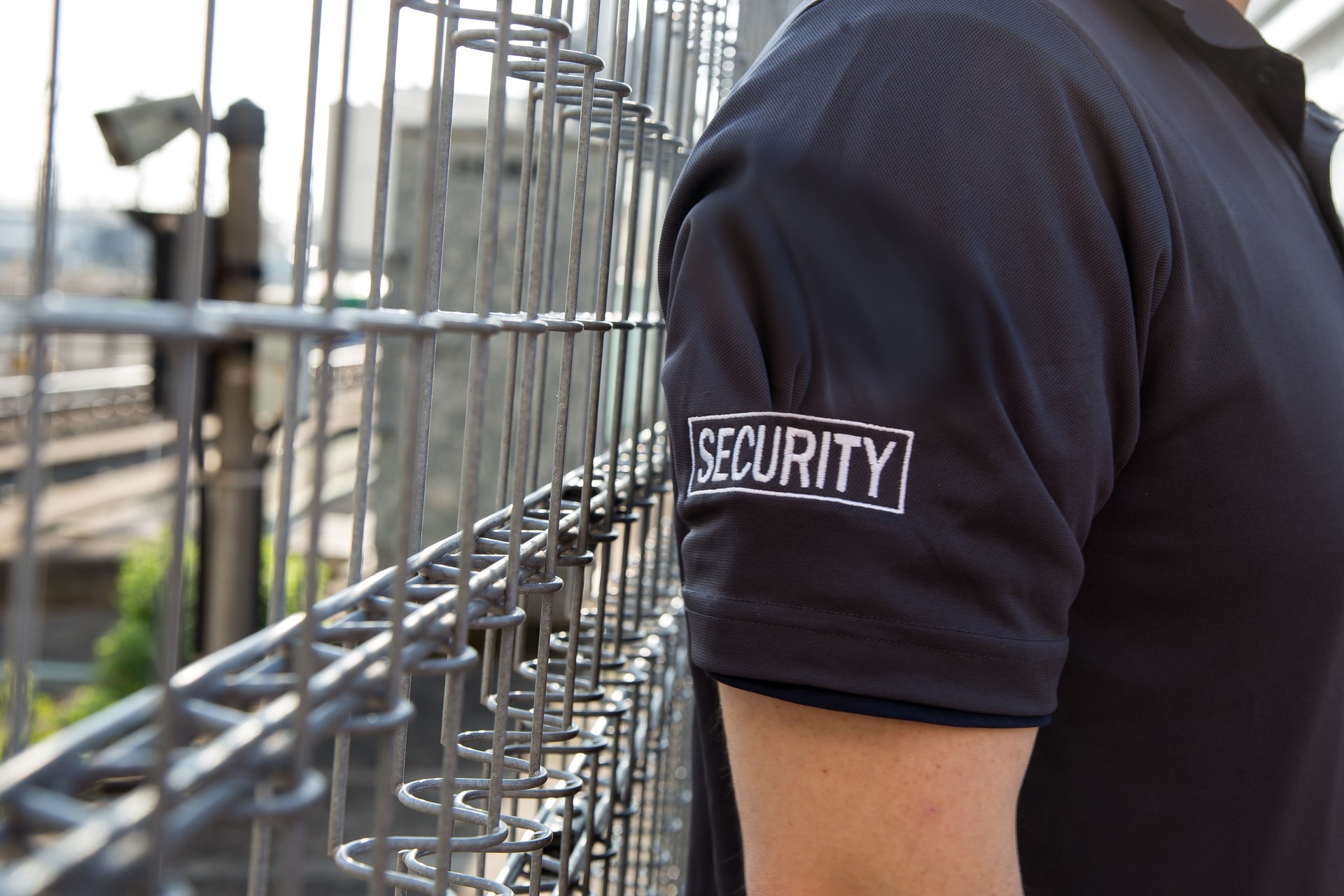 Security guard in uniform patrolling residential area nearby railway.